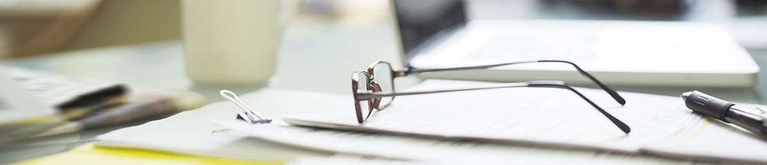 A pair of eyeglasses sitting on a stack of papers